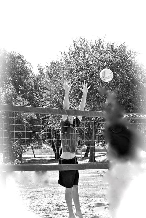 A player leaping to block at the net during the Italian Stallion Open sand volleyball tournament