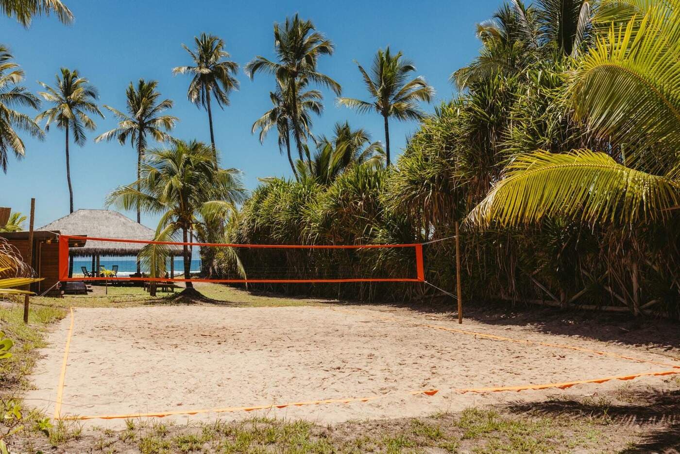 An empty sand volleyball court with the net strung across it